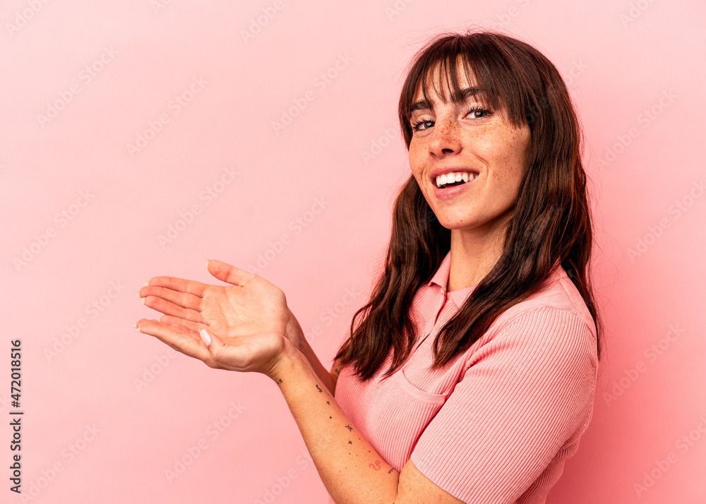 Young Argentinian woman isolated on pink background holding a copy space on a palm. Young Argentinian woman isolated on pink background holding a copy space on a palm.