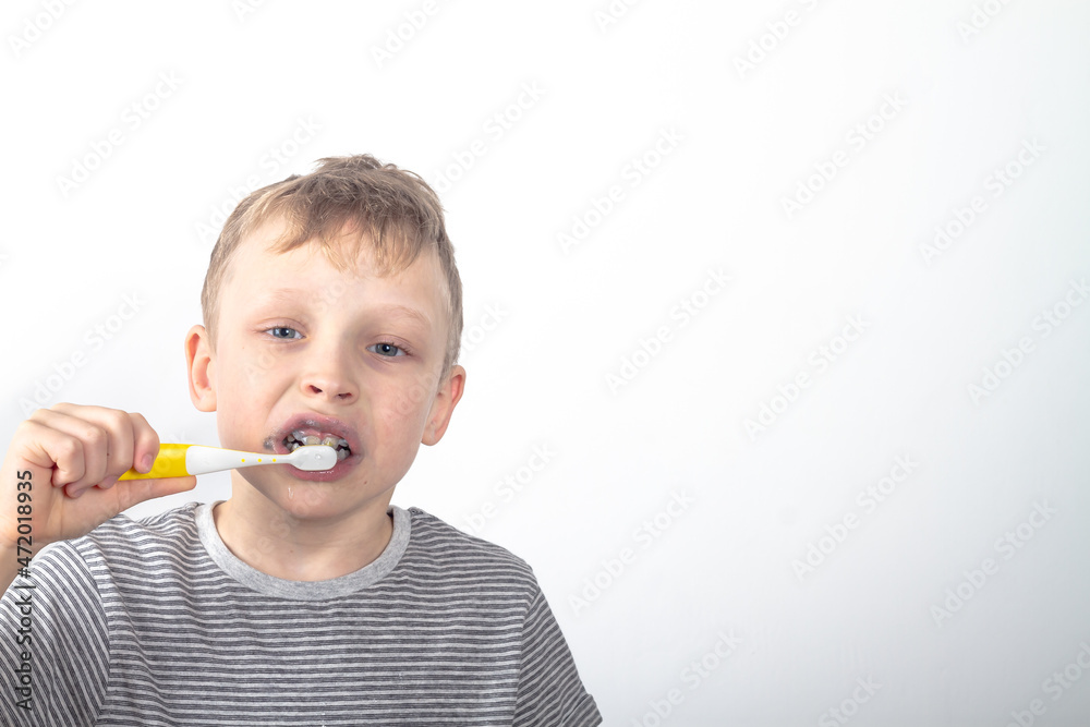 Caucasian boy brushes his teeth with black toothpaste with charcoal Caucasian boy brushes his teeth with black toothpaste with charcoal