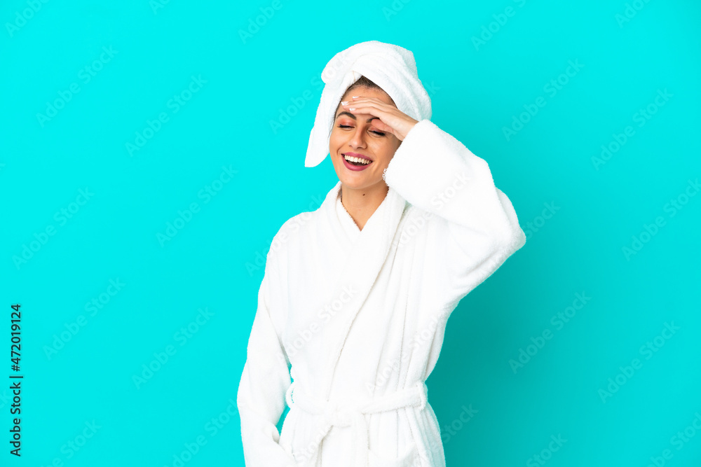Young woman in a bathrobe over isolated blue background smiling a lot Young woman in a bathrobe over isolated blue background smiling a lot
