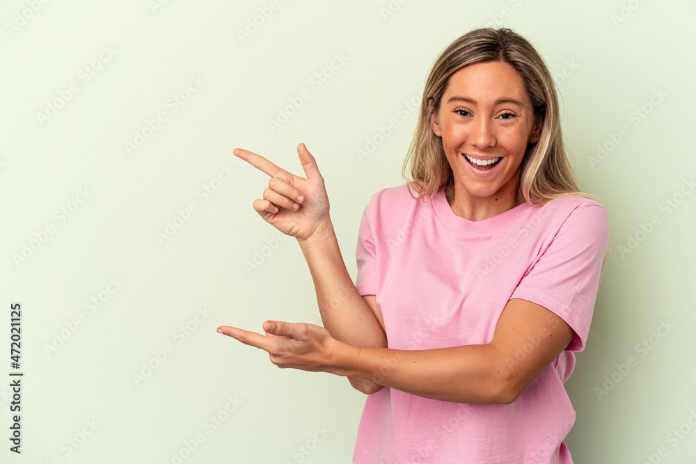 Young caucasian woman isolated on green background excited pointing with forefingers away. Young caucasian woman isolated on green background excited pointing with forefingers away.
