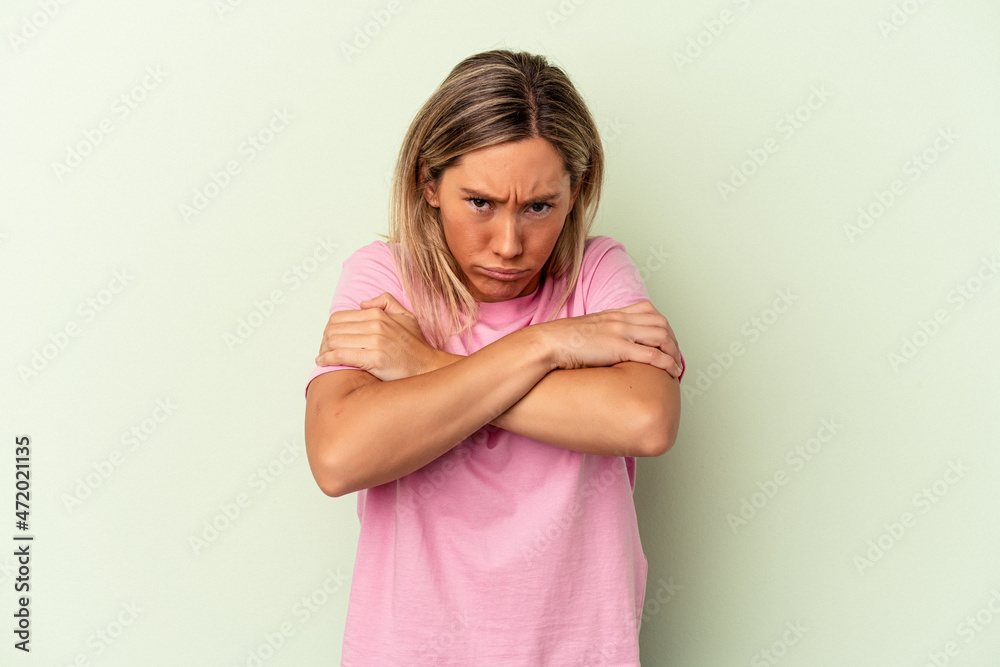 Young caucasian woman isolated on green background shrugs shoulders and open eyes confused. Young caucasian woman isolated on green background shrugs shoulders and open eyes confused.