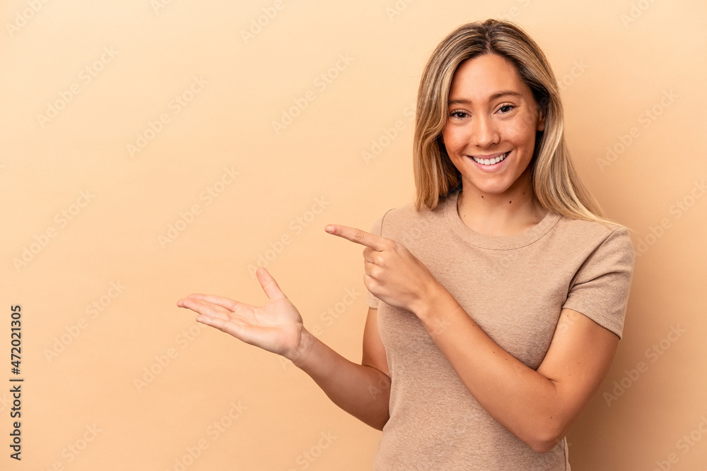 Young caucasian woman isolated on beige background excited holding a copy space on palm. Young caucasian woman isolated on beige background excited holding a copy space on palm.
