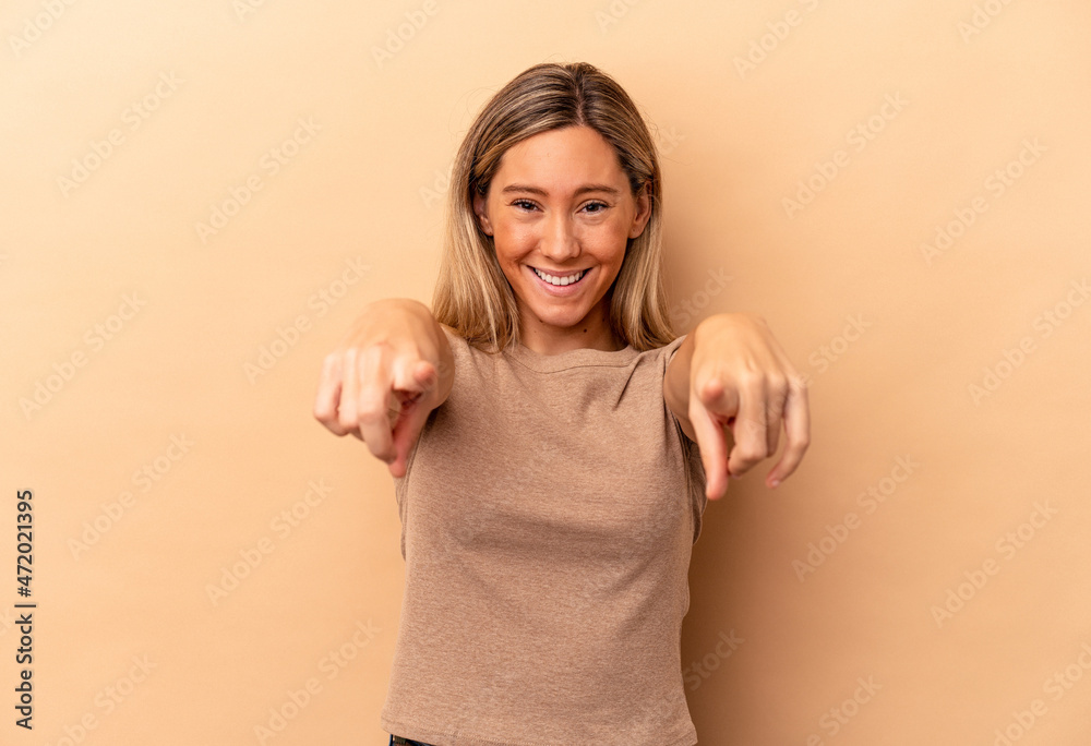 Young caucasian woman isolated on beige background cheerful smiles pointing to front. Young caucasian woman isolated on beige background cheerful smiles pointing to front.