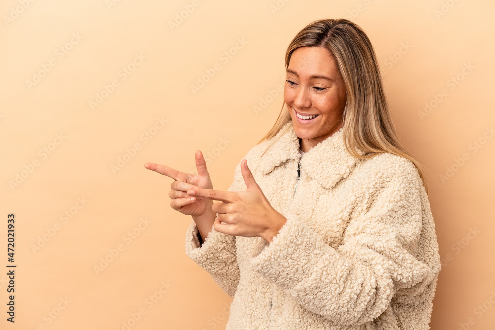 Young caucasian woman isolated on beige background points with thumb finger away, laughing and carefree. Young caucasian woman isolated on beige background points with thumb finger away, laughing and carefree.