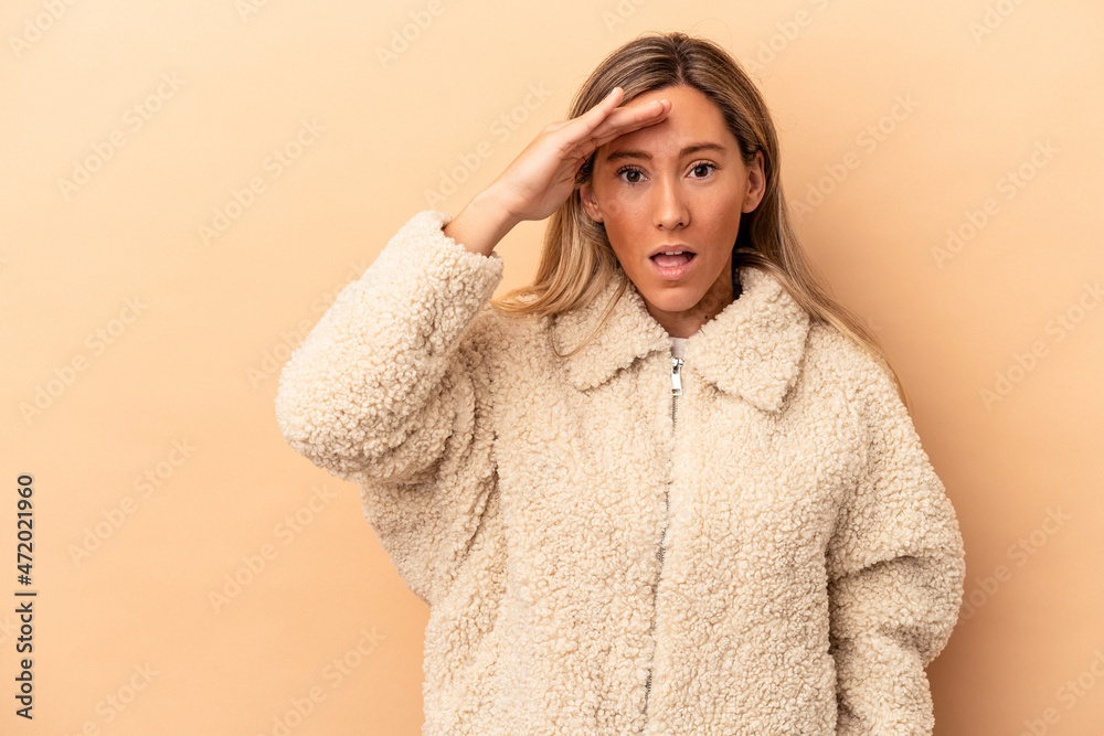 Young caucasian woman isolated on beige background looking far away keeping hand on forehead. Young caucasian woman isolated on beige background looking far away keeping hand on forehead.