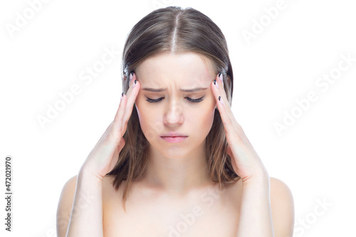 Photo of a young beautiful girl experiencing an attack of severe headache, standing with her hands near her head on a white background