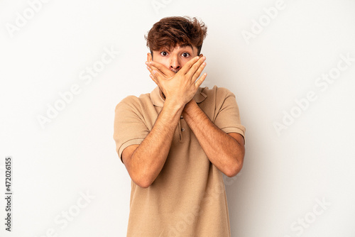 Young mixed race man isolated on grey background shocked covering mouth with hands.