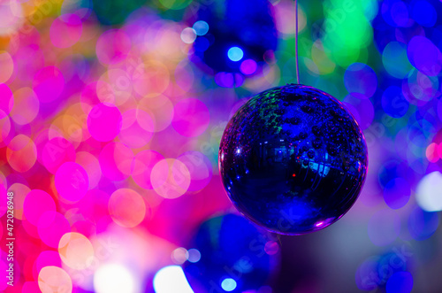 Blue bauble hanging to decorate for Christmas holiday with colorful bokeh from light and other baubles.