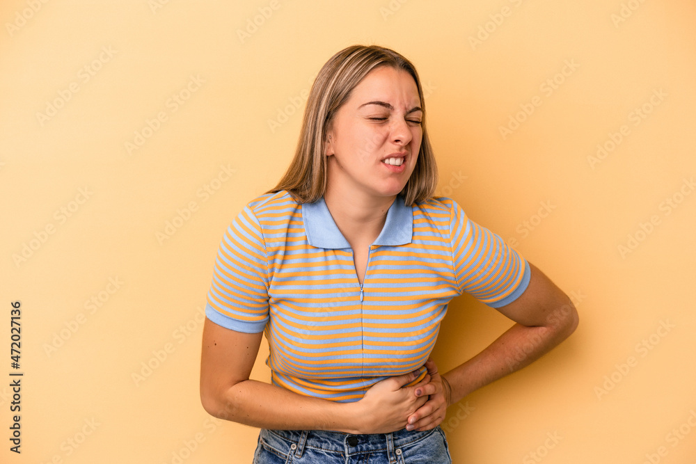 Young caucasian woman isolated on yellow background having a liver pain, stomach ache. Young caucasian woman isolated on yellow background having a liver pain, stomach ache.