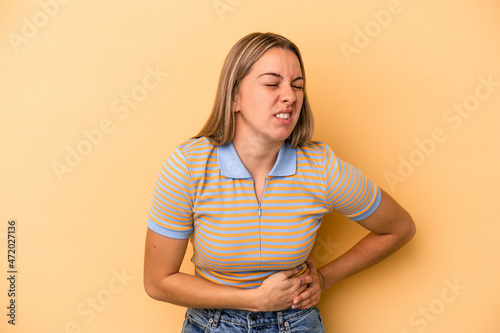 Young caucasian woman isolated on yellow background having a liver pain, stomach ache.