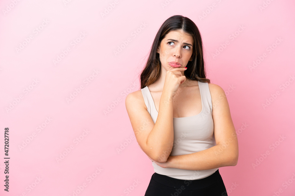 Young Italian woman isolated on pink background having doubts and thinking Young Italian woman isolated on pink background having doubts and thinking