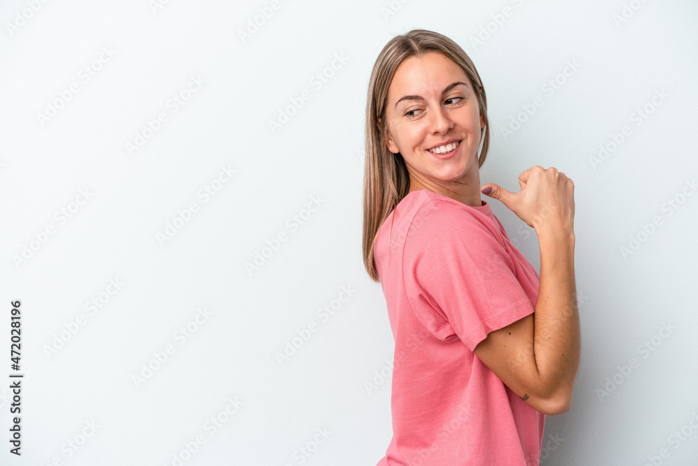 Young caucasian woman isolated on blue background points with thumb finger away, laughing and carefree.