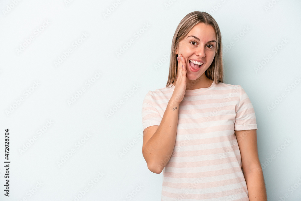 Young caucasian woman isolated on blue background shouts loud, keeps eyes opened and hands tense. Young caucasian woman isolated on blue background shouts loud, keeps eyes opened and hands tense.