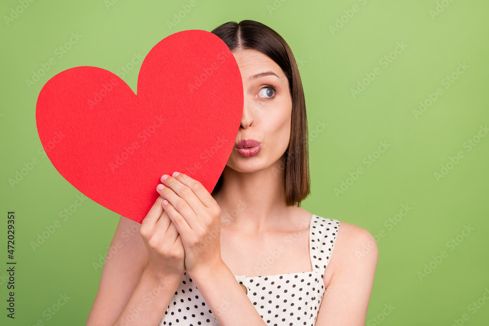 Photo of sweet millennial brunette lady close heart look wear dotted overall isolated on green color background Photo of sweet millennial brunette lady close heart look wear dotted overall isolated on green color background