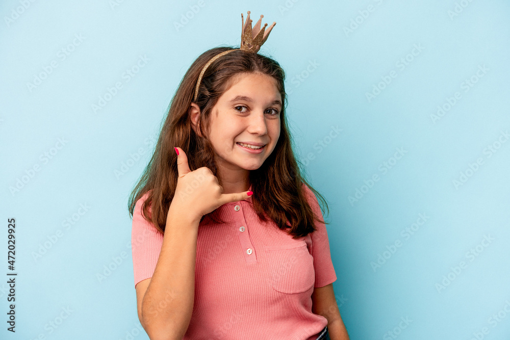 Little caucasian girl wearing a princess crown isolated on blue background showing a mobile phone call gesture with fingers. Little caucasian girl wearing a princess crown isolated on blue background showing a mobile phone call gesture with fingers.