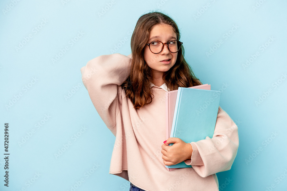 Little caucasian student girl holding books isolated on blue background touching back of head, thinking and making a choice. Little caucasian student girl holding books isolated on blue background touching back of head, thinking and making a choice.