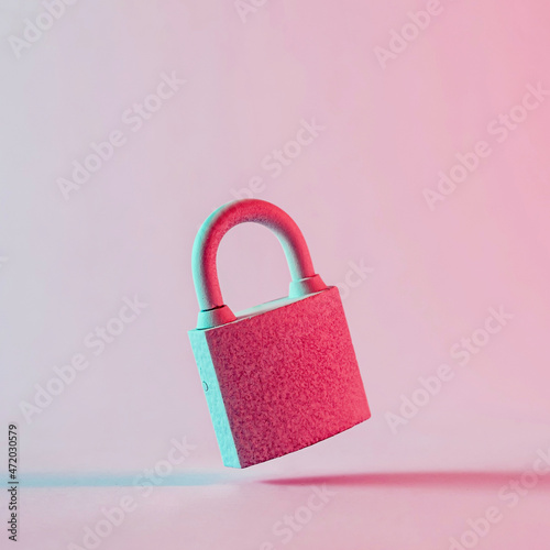 Close-up of an old padlock floating over pink background photo