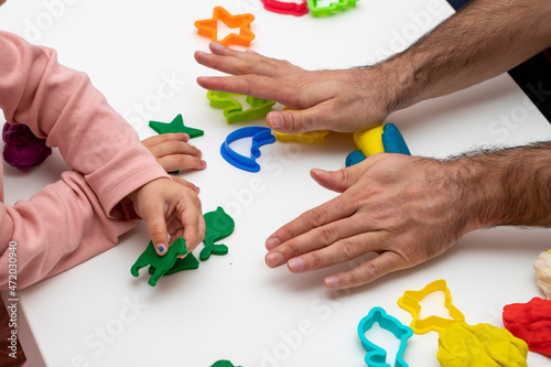 Girl playing dough with her father. father daughter playing game on white background. Making various shapes with dough. Close-up. Father's Day.