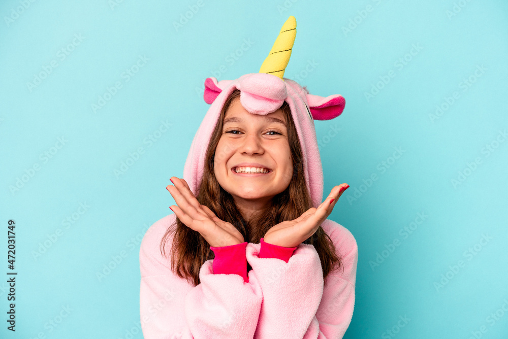 Little caucasian girl wearing a unicorn pajama isolated on pink background