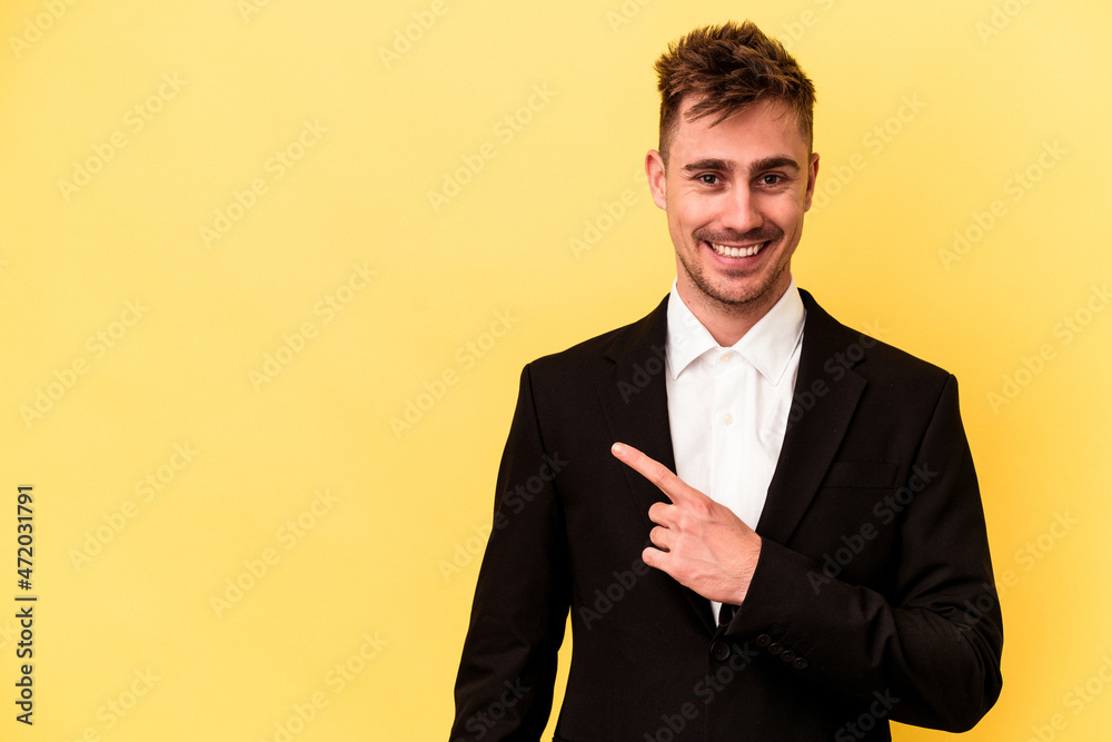 Young caucasian business man isolated on yellow background smiling and pointing aside, showing something at blank space. Young caucasian business man isolated on yellow background smiling and pointing aside, showing something at blank space.