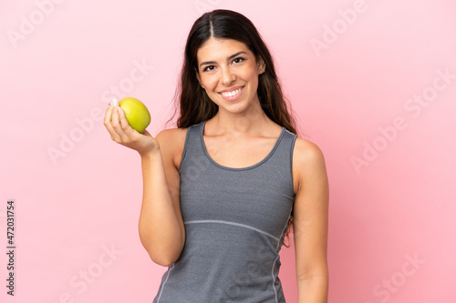 Young caucasian woman isolated on pink background with an apple