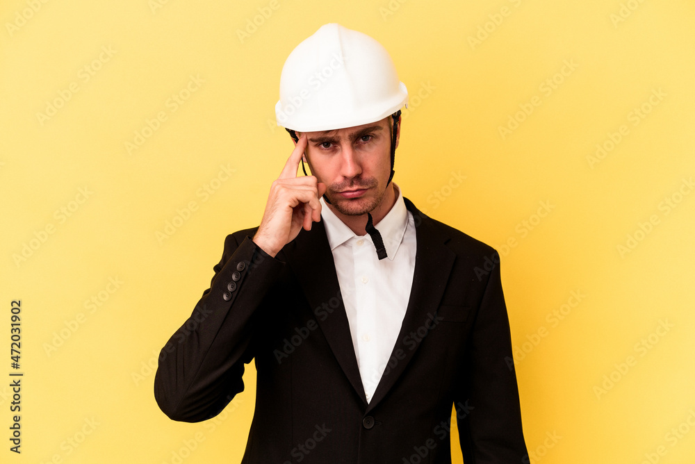 Young architect caucasian man isolated on yellow background pointing temple with finger, thinking, focused on a task. Young architect caucasian man isolated on yellow background pointing temple with finger, thinking, focused on a task.