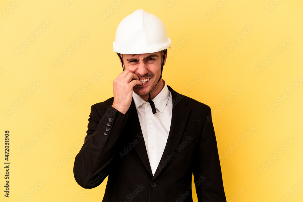 Young architect caucasian man isolated on yellow background biting fingernails, nervous and very anxious. Young architect caucasian man isolated on yellow background biting fingernails, nervous and very anxious.