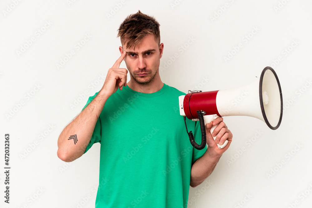 Young caucasian man holding megaphone isolated on white background pointing temple with finger, thinking, focused on a task. Young caucasian man holding megaphone isolated on white background pointing temple with finger, thinking, focused on a task.