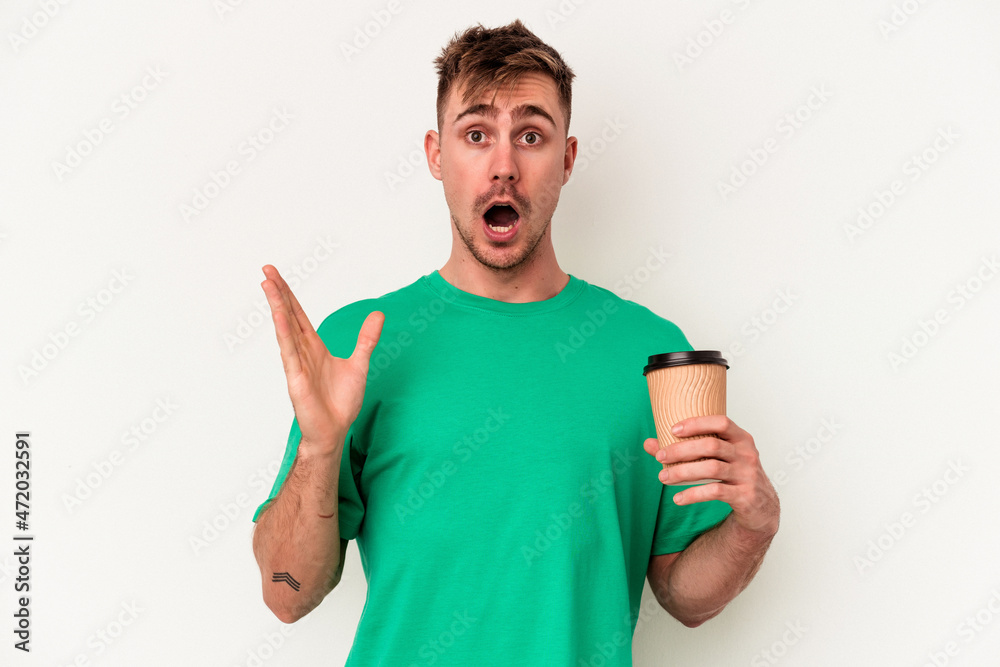 Young caucasian man holding a take away coffee isolated on white background surprised and shocked.