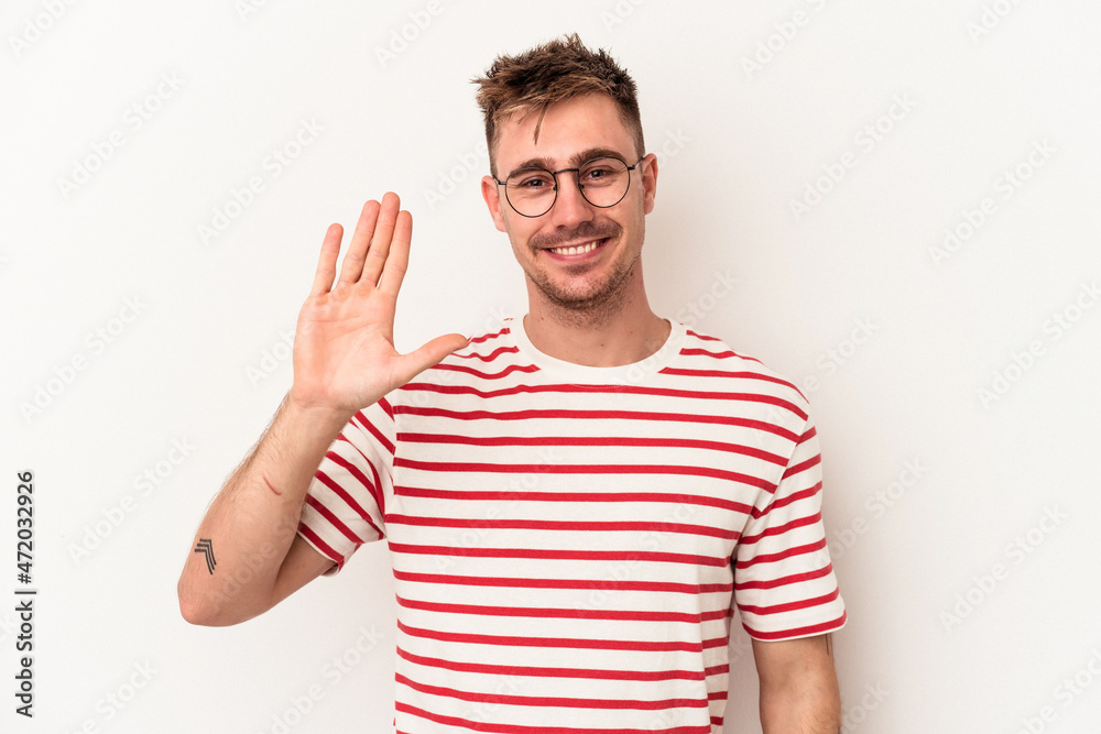 Naklejka premium Young caucasian man isolated on white background smiling cheerful showing number five with fingers.