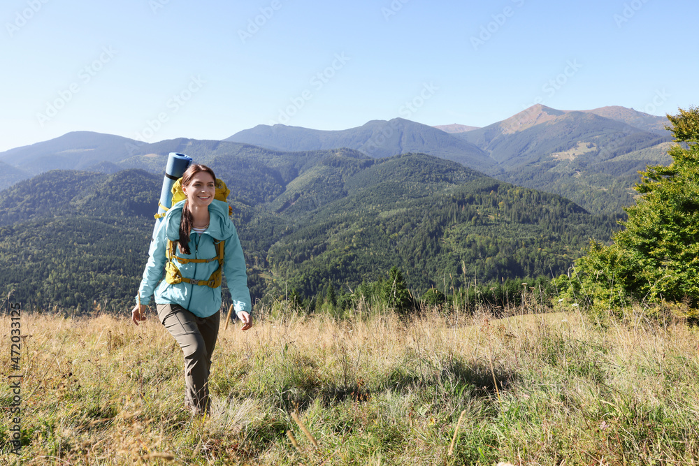 Tourist with backpack walking in mountains on sunny day