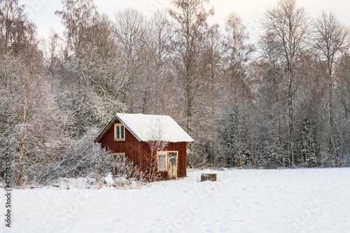 Red shed on a snowy meadow by the forest © Lars Johansson