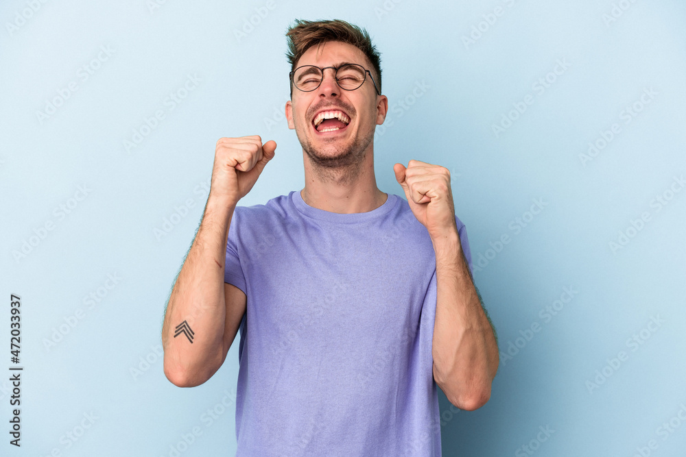Fototapeta premium Young caucasian man isolated on blue background celebrating a victory, passion and enthusiasm, happy expression.