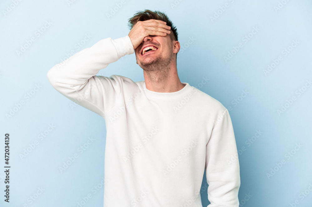 Young caucasian man isolated on blue background laughs joyfully keeping hands on head. Happiness concept. Young caucasian man isolated on blue background laughs joyfully keeping hands on head. Happiness concept.