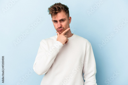 Young caucasian man isolated on blue background contemplating, planning a strategy, thinking about the way of a business.