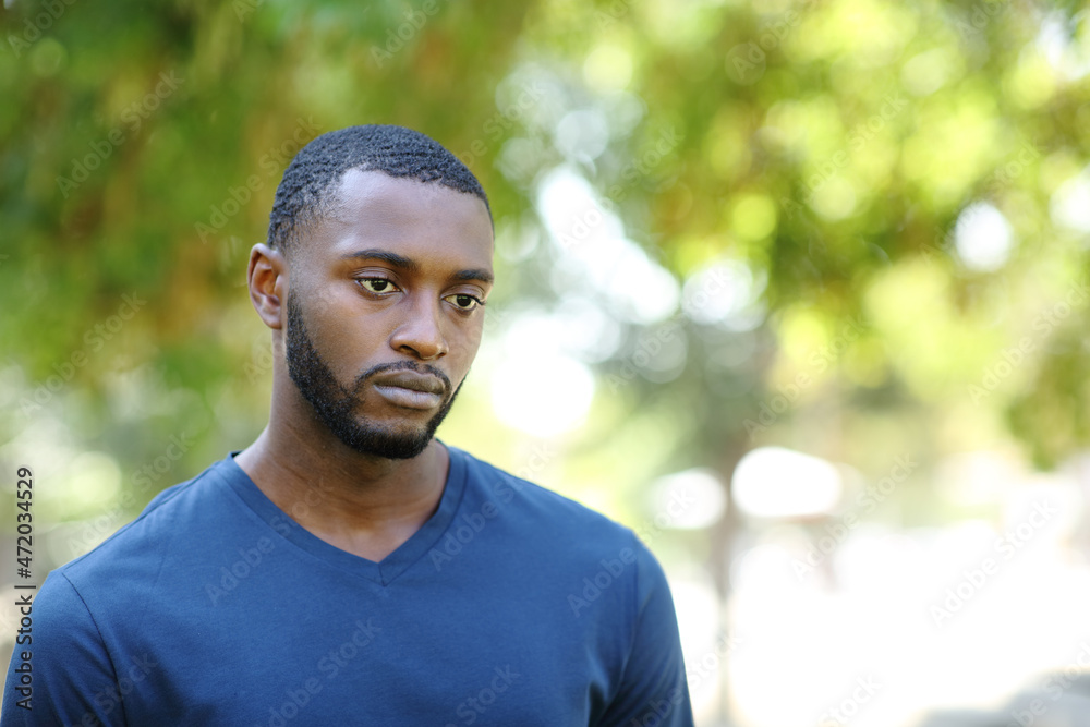 Fototapeta premium Worried man with black skin distracted looking away in a park