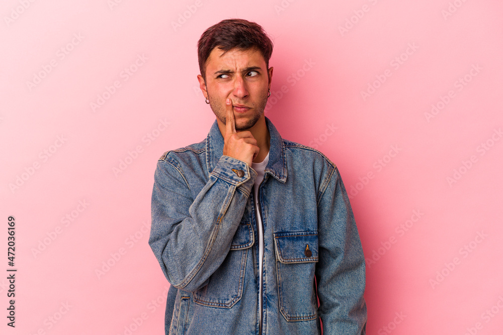 Fototapeta premium Young caucasian man with tattoos isolated on yellow background looking sideways with doubtful and skeptical expression.
