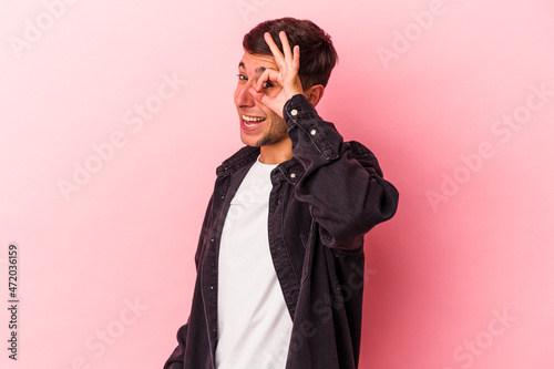 Young caucasian man with tattoos isolated on yellow background excited keeping ok gesture on eye.