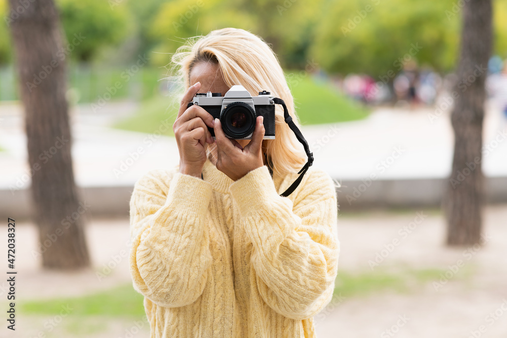 Woman taking a photo with a camera in a park