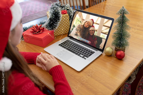 Caucasian woman in santa hat making laptop christmas video call with smiling mother and daughter