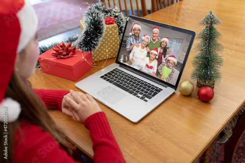 Caucasian woman in santa hat making laptop christmas video call with smiling multi generation family