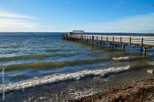 a long wooden pier in Herrsching on lake Ammersee on a fresh windy day with blue sky in December  Bavaria  Germany 