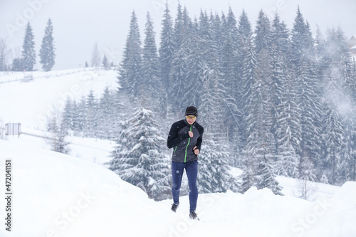 Young man running in mountains in winter cold weather