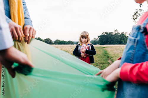 Girl collecting plastic bottles with family in park