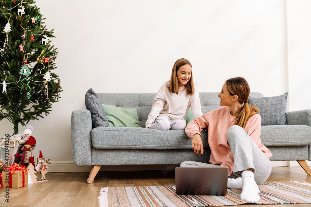 White mother and daughter smiling and using laptop at home White mother and daughter smiling and using laptop at home