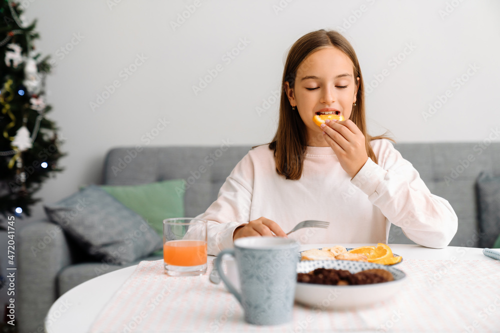 White blonde girl eating orange while having breakfast White blonde girl eating orange while having breakfast