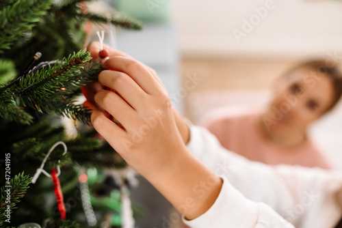 White mother and daughter decorating christmas tree at home