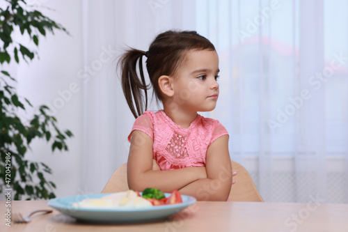 Cute little girl refusing to eat her breakfast at home photo