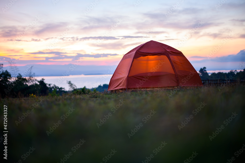 Illuminated orange Camping tent at sunrise.