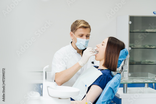 Caucasian male dentist examining young woman patient s teeth at dental clinic. Doctor probing teeth with dental instrument using an explorer look for cavities treatment and checking problems